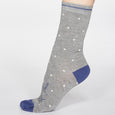 side view of a pair of grey bamboo socks with blue toe and heel, white polka dots and 'And Relax' printed on them.