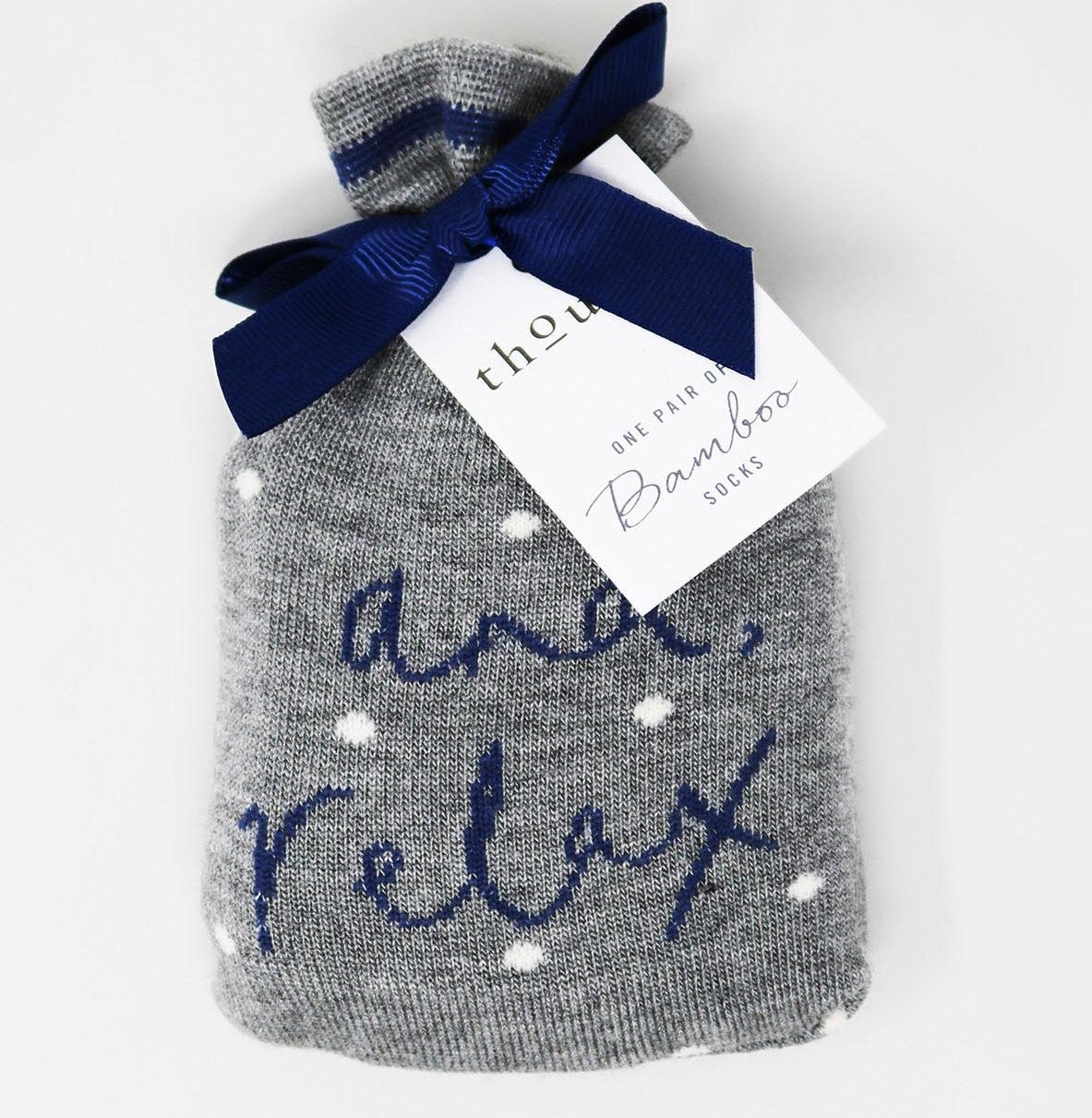 A gift bag of two pairs of grey bamboo socks with the phrase 'And Relax' embroidered on them